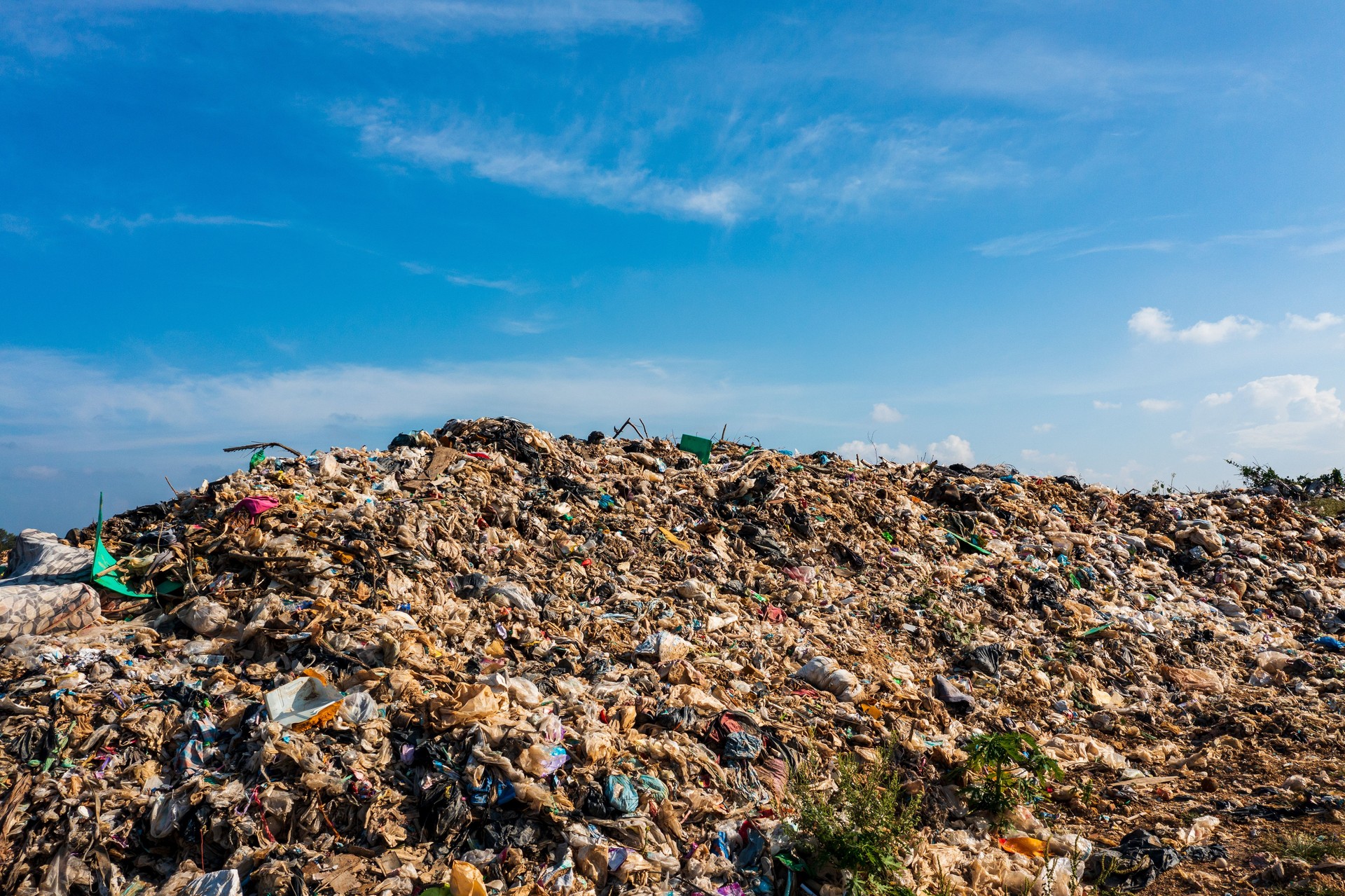 A sprawling landfill stretches across the horizon, a stark testament to the sheer volume of waste generated by human consumption.
